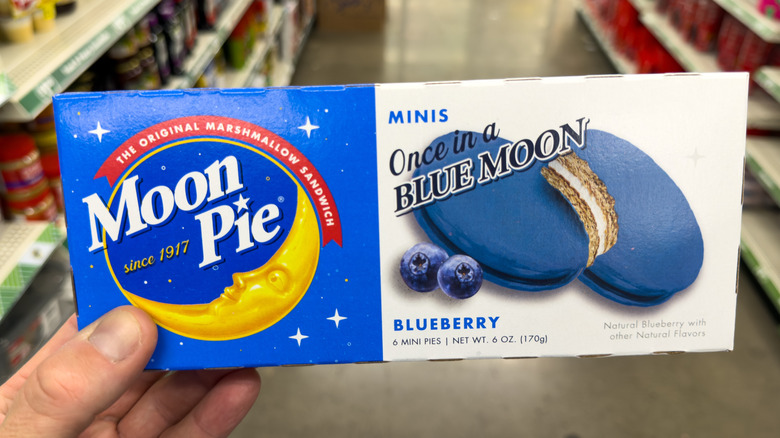 A person holding MoonPie Once in a Blue Moon Mini Pies in a Dollar Store aisle