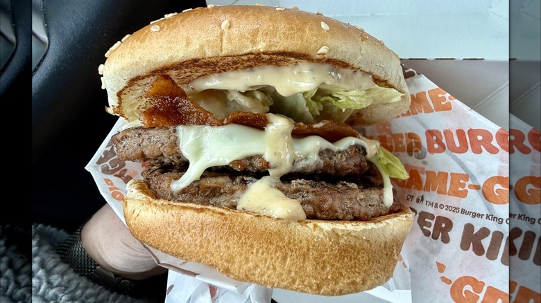 Person holding a peppercorn BLT Whopper from Burger King.