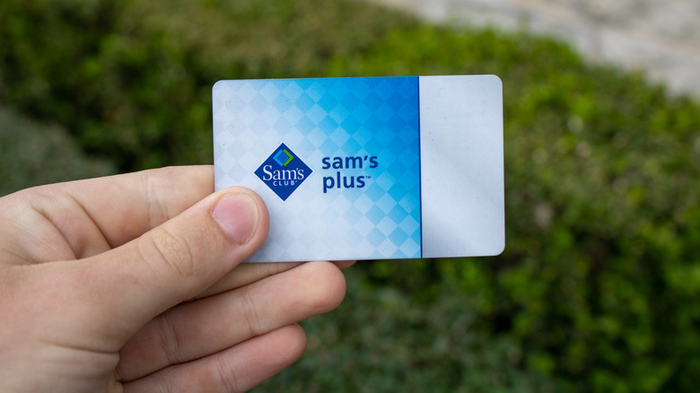 Hand holding Sam's Plus card outside.