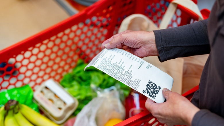 Shopper looking at their receipt inside a grocery store.