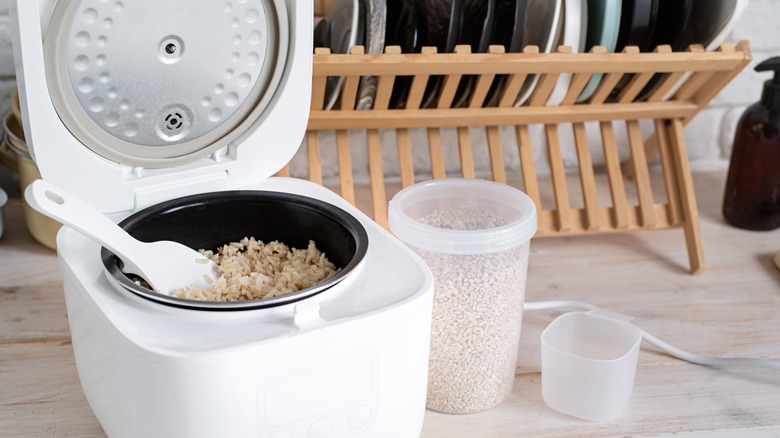 Open rice cooker with canister of rice and scoop