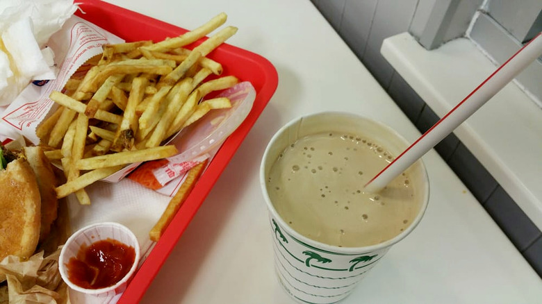 A burger and fries on a red tray with a chocolate milkshake from In-N-Out Burger