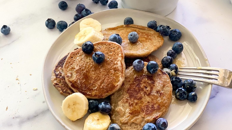 Pancakes, blueberries, and banana slices sitting on a plate