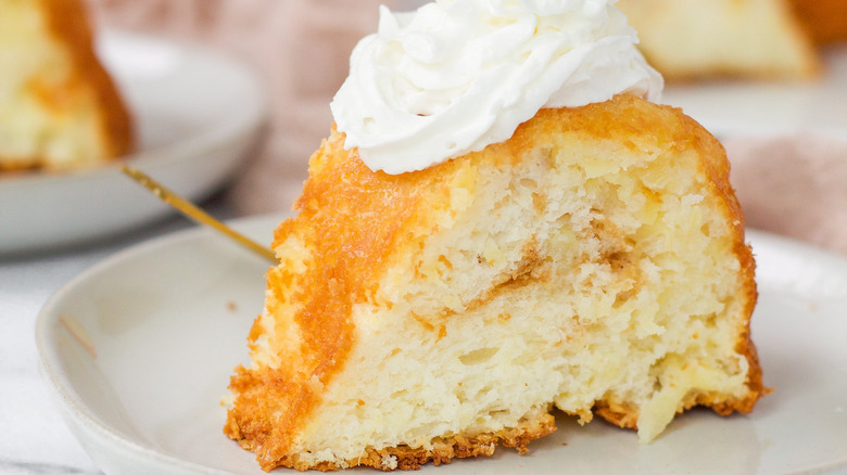 Close up of a slice of angel food cake topped with whipped cream