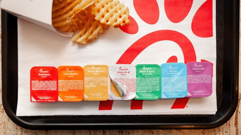 Chick-fil-A waffle fries on tray with row of various dipping sauces.