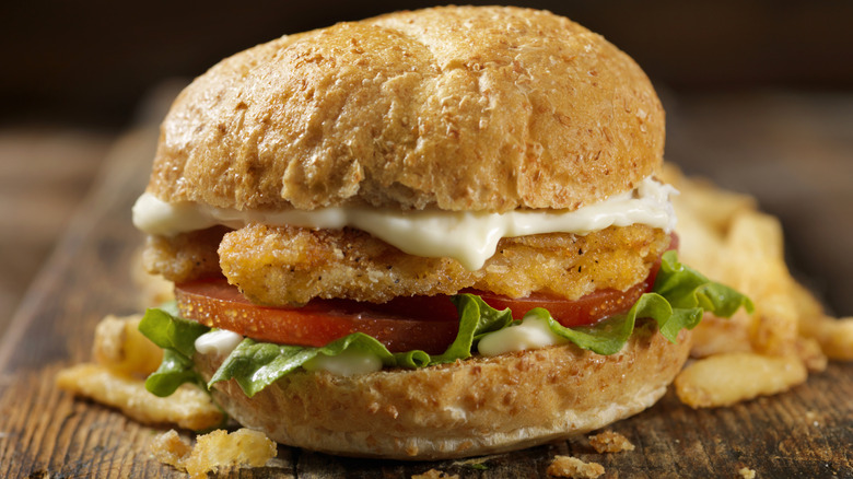 Chicken sandwich with mayonnaise, tomatoes, and lettuce.