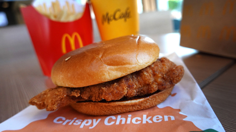 McDonald's crispy chicken sandwich with fries and a drink on restaurant table.