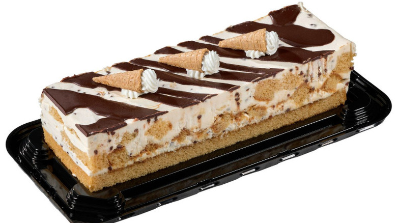 A chocolate and vanilla bar cake topped with three small waffle cones on plastic serving tray.