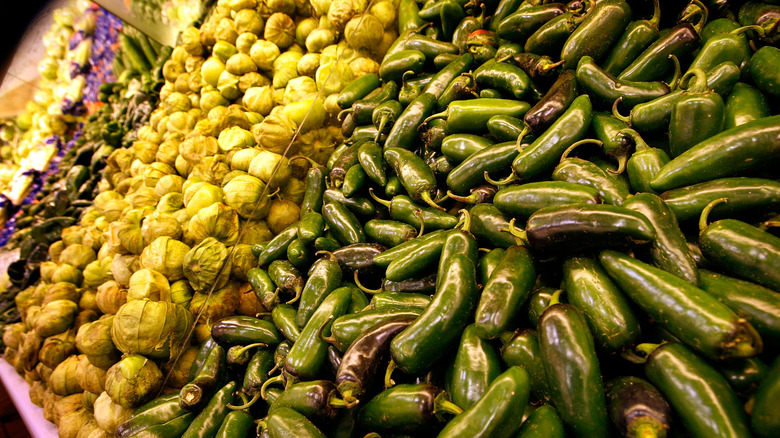 Jalapeño peppers, tomatillos, and other produce items on display inside a supermarket