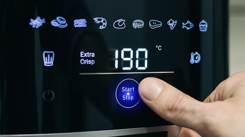 Person pressing a button on an air fryer.