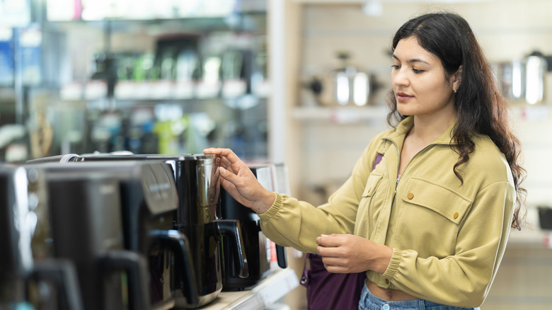 Person shopping for new air fryer in department store.