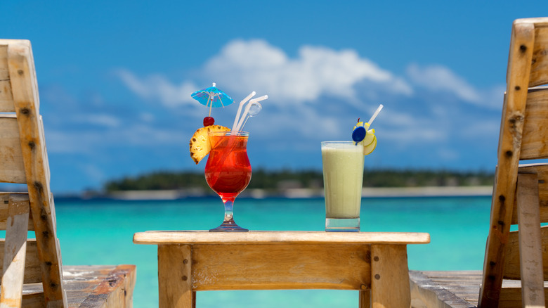 Two tropical cocktails on table by a Caribbean beach.