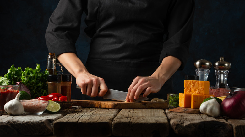 Person cutting with knife on wood cutting board