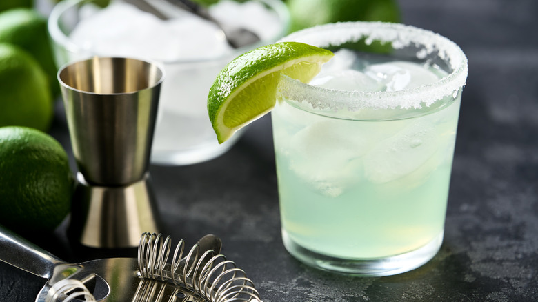 A margarita cocktail in a short glass with a salted rim and lime garnish.