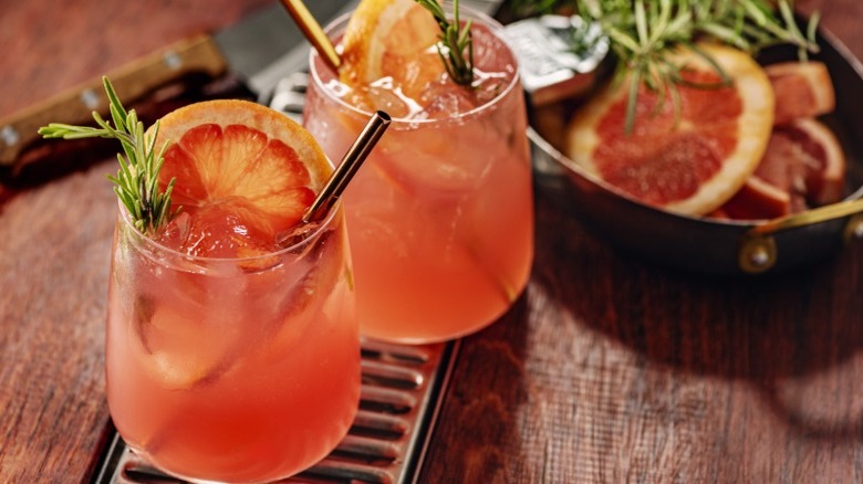 Two paloma cocktails with grapefruit and rosemary garnish.
