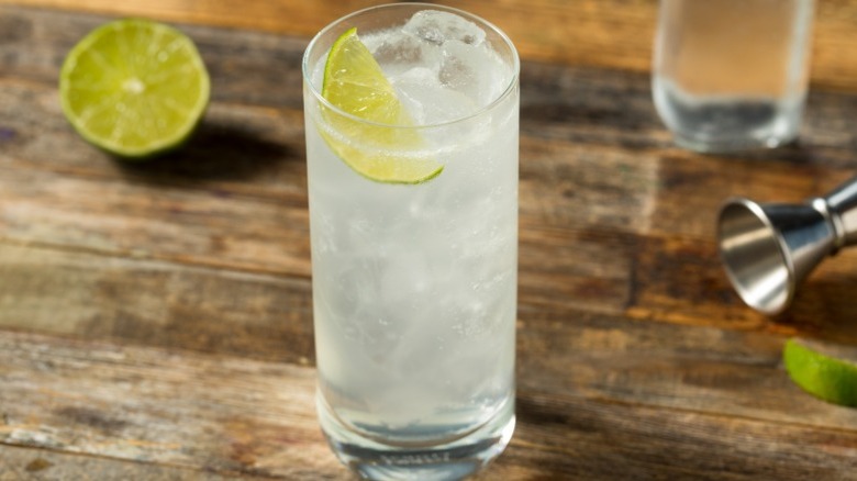 A ranch water cocktail with lime slice on wooden table.