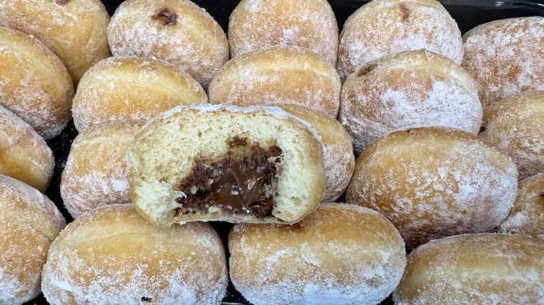 half eaten chocolate filled beignet on stack of full ones