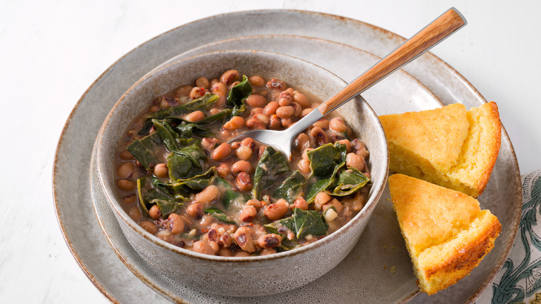 Bowl with black eyed peas and collard greens with cornbread on the side