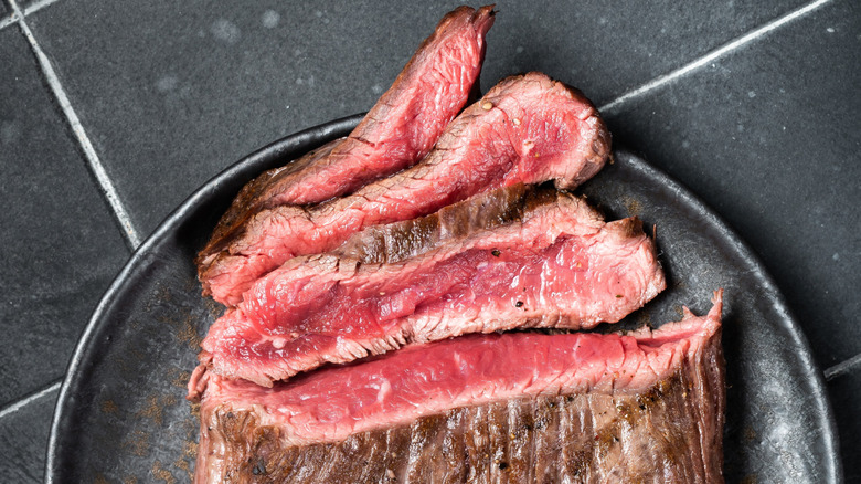 Closeup of sliced rare flap steak on black plate