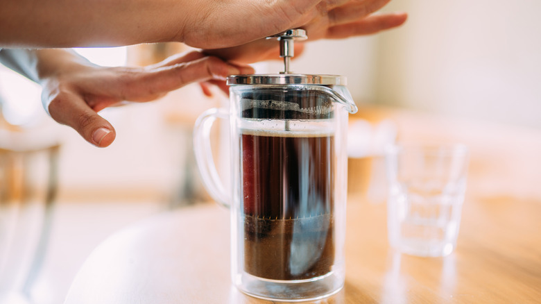 Hands plunging French press coffee top