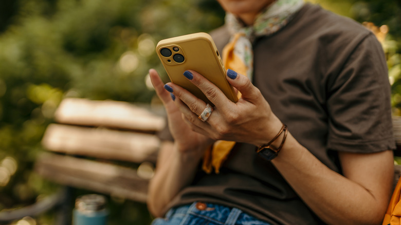 Person using smartphone on a park bench