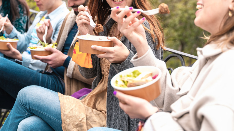 People eating on park bench