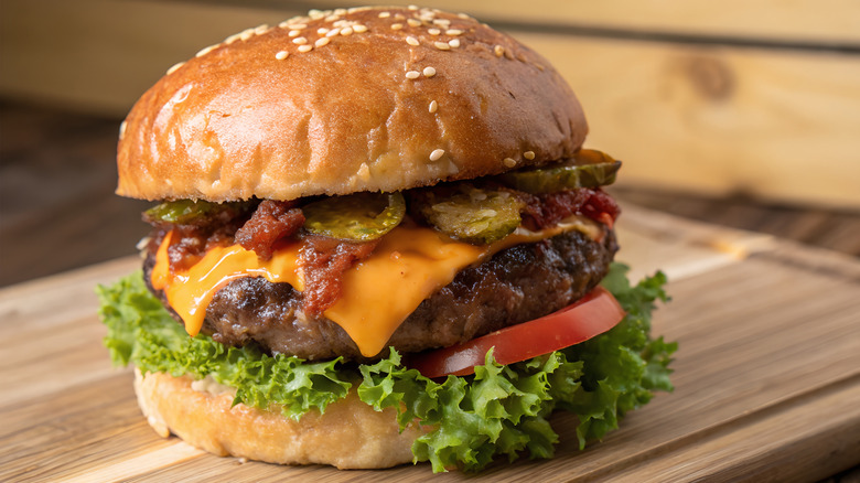 Cheeseburger with toppings on a wooden cutting board