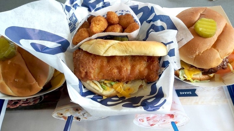 A Culver's fish sandwich surrounded by an order of cheese curds and a burger on each side