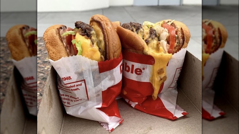 Two loaded burgers from In-N-Out side by side in a paper tray.