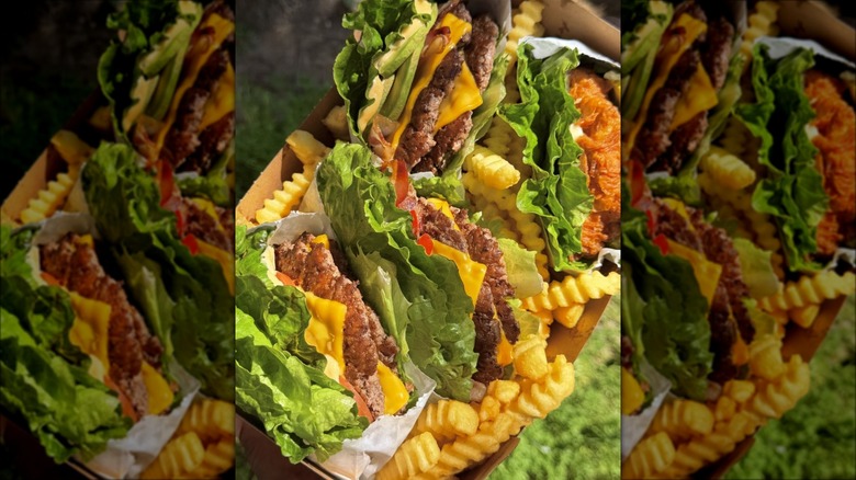 Lettuce-wrapped Shake Shack burgers and sandwiches on tray with crinkle fries.