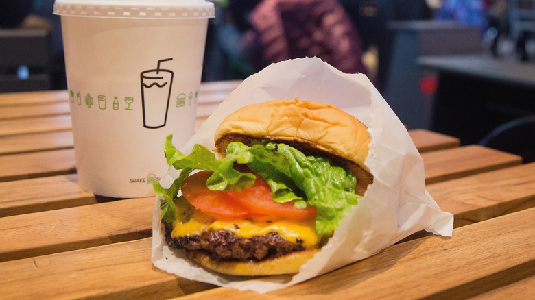 Shake Shack burger and beverage on table inside restaurant.