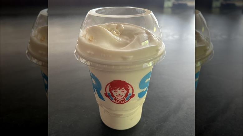 A small vanilla Frosty from Wendy's in a plastic cup.
