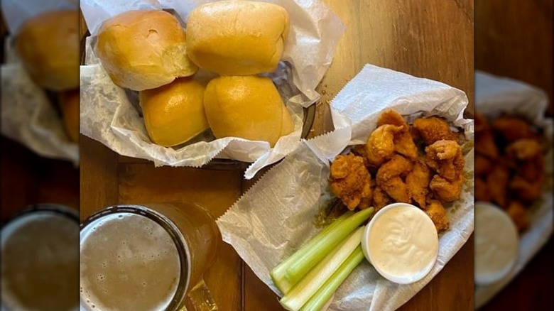 Baskets of dinner rolls and boneless Buffalo wings with mug of beer on table at Texas Roadhouse.