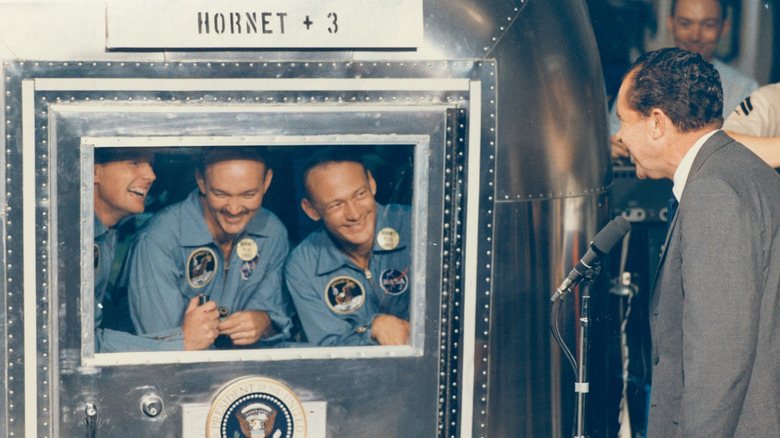 Apollo 11 astronauts in Hornet capsule while President Nixon looks on.