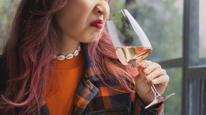 Person smelling bad wine and wrinkling their nose.