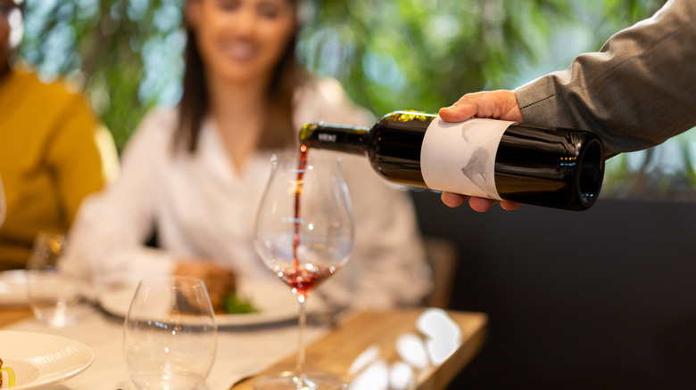 Pouring a bottle of red wine at a restaurant