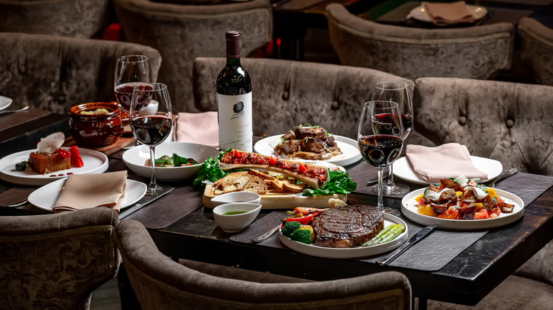 Restaurant meal of steak and high-end dishes with red wine