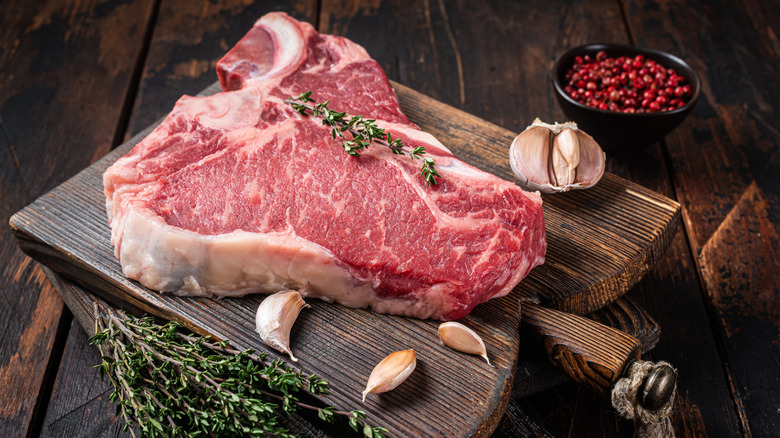 raw T-bone steak on cutting board