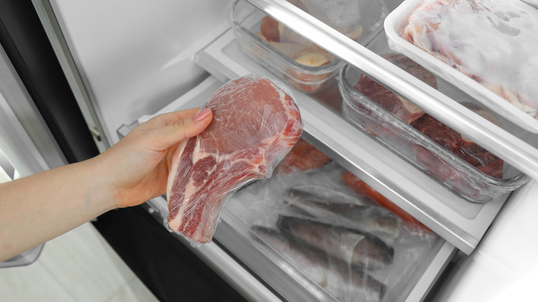 person taking frozen steak out of the freezer
