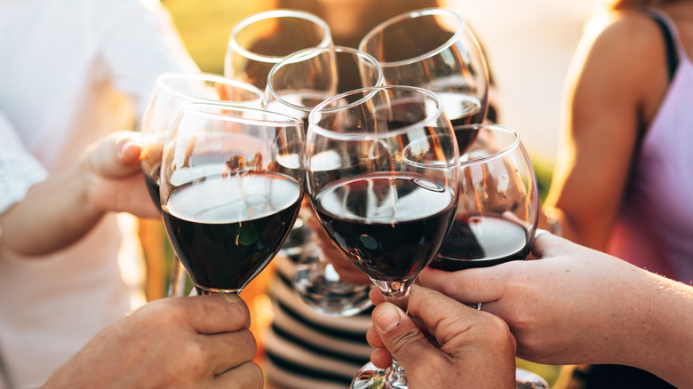 People clinking wine glasses together