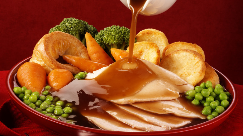 Gravy being poured over a plate of turkey