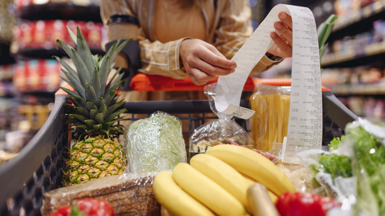 Full supermarket trolley and customer holding receipt