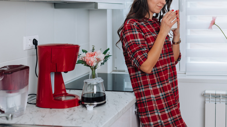 Person in a nightgown holding coffee from a drip maker