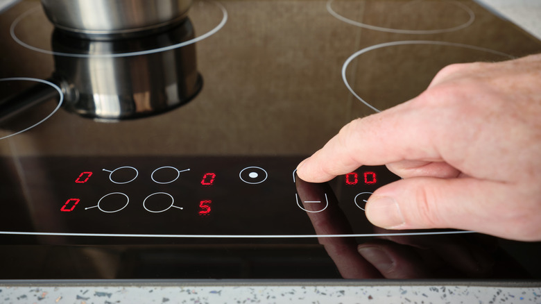 Closeup of a person turning up the heat on an induction stovetop