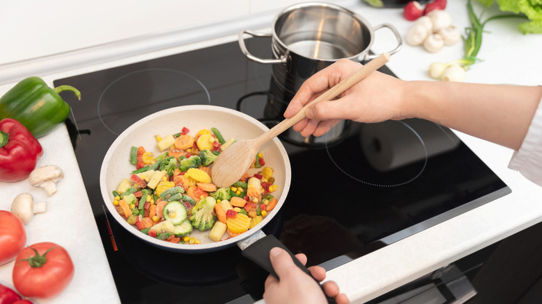 Sauteeing fresh vegetables in a pan on an induction stovetop