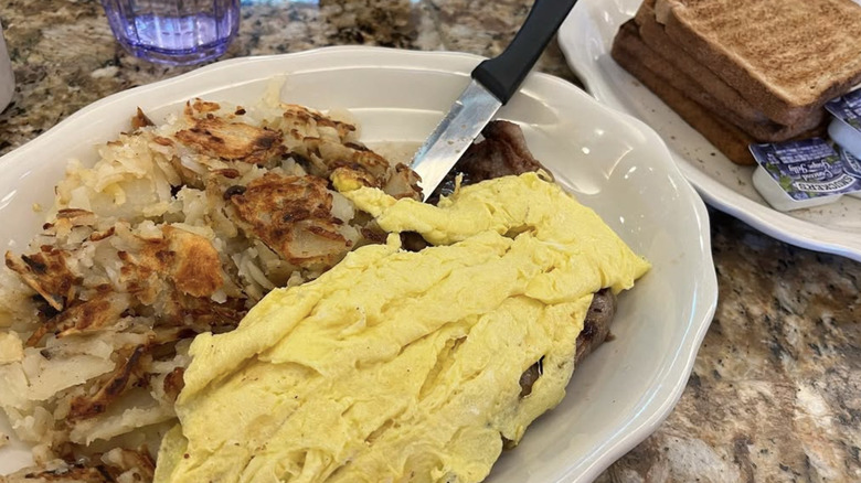 A knife jabbed into a pile of hash browns and scrambled eggs at Court Square Diner