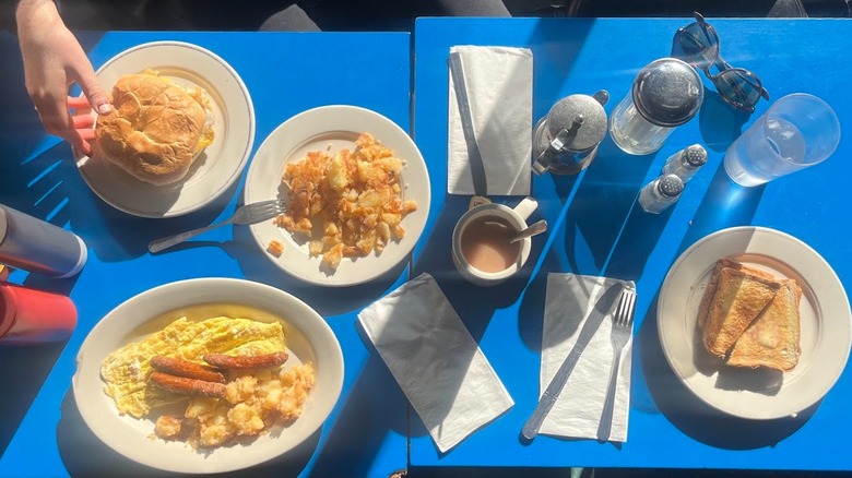 Light raking across a blue table covered in breakfast items at a diner