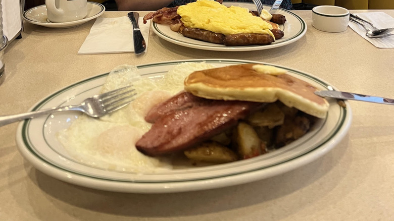 Egga, kielbasa, potatoes, and pancakes resting on an oval plate at Three Decker Diner