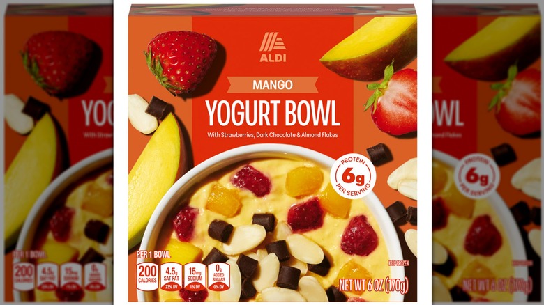 A colorful box featuring the mango yogurt bowl surrounded by chunks of mango and strawberry, almond slivers, and chocolate morsels.