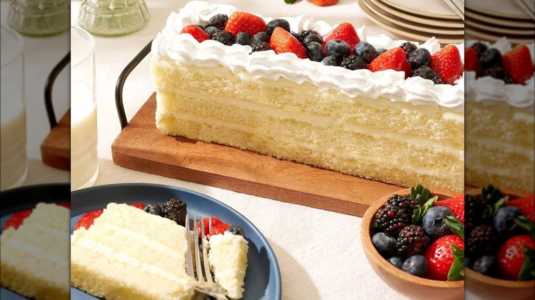 Slice of Chantilly cake on plate with full cake in the background.